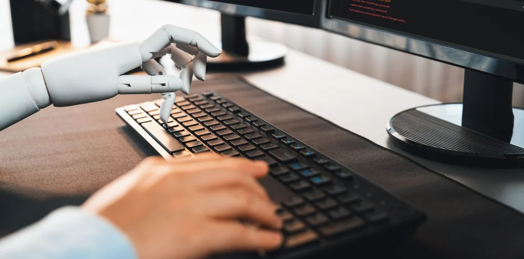 Yapay zeka destekli robot eli ve insanın birlikte klavye üzerinde çalışması